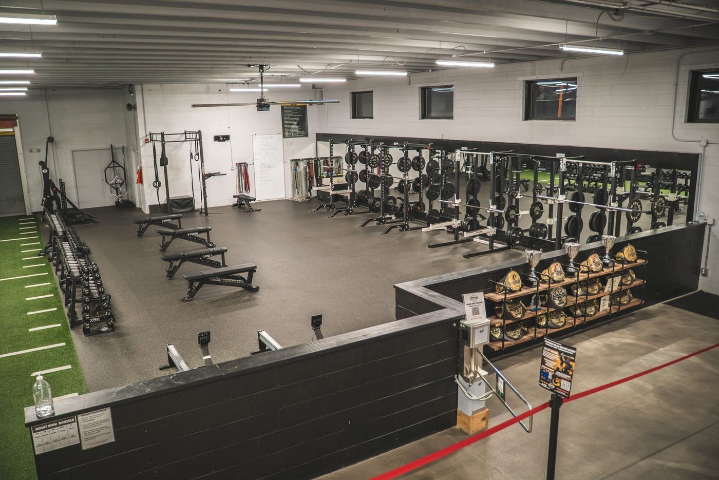 Weight room with racks, benches and the championship belt wall