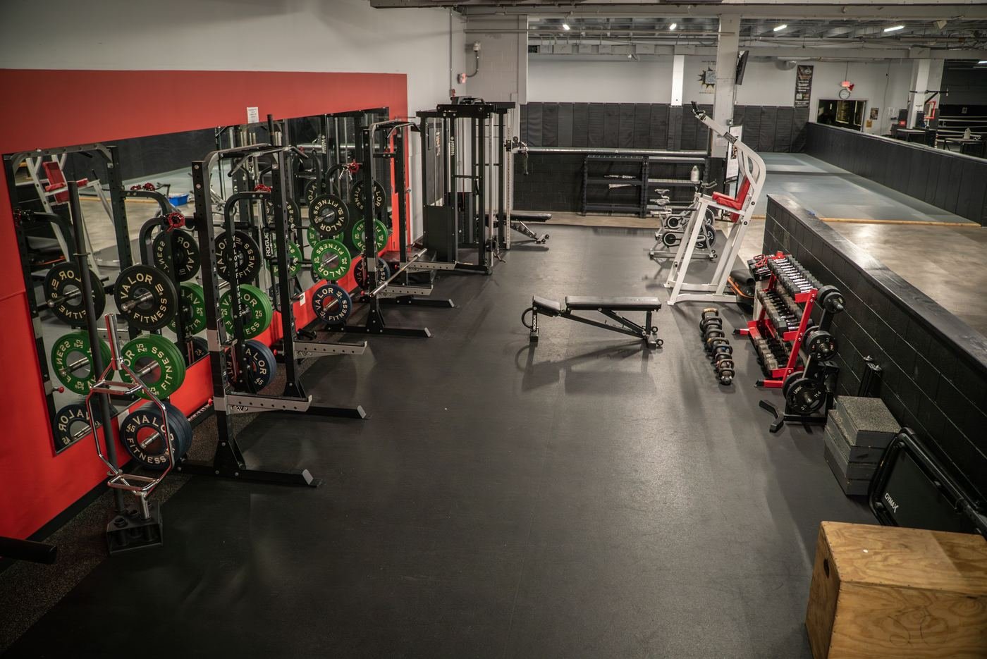 Squat racks and free weights along the red mirror wall